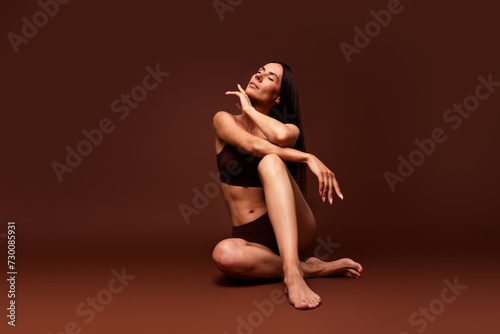 Full size photo no filter of attractive young woman sit floor salon treatment dressed stylish underwear isolated on brown color background