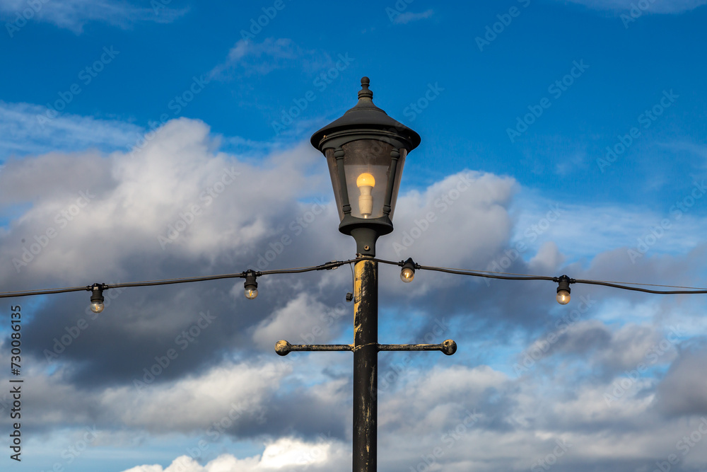 A decorative street lamp and string lights on Skegness seafront, with a blue sky behind A decorative street lamp and string lights on Skegness seafront, with a blue sky behind