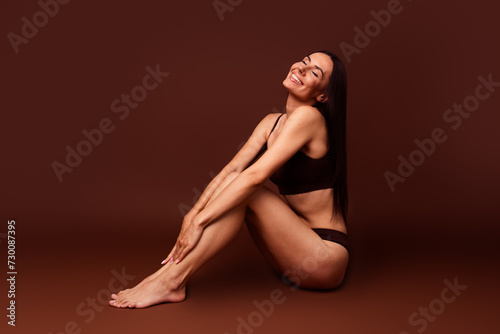Full size photo no filter of attractive young woman sit floor enjoy procedure dressed stylish underwear isolated on brown color background