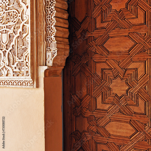 Ornamental detail of the decorative richness of the Alhambra in Granada, mixing the plasterwork with the starry geometric motifs carved in wood on a palace door.