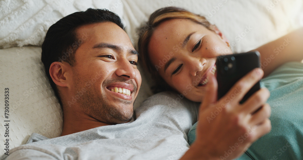 Phone, social media and communication with a couple in bed to relax, laughing and relaxing in the bedroom of the home together. Diversity, internet and mobile with a man and woman happy in the house - obrazy, fototapety, plakaty 