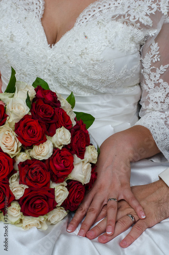 hands of married couple with rings and roses