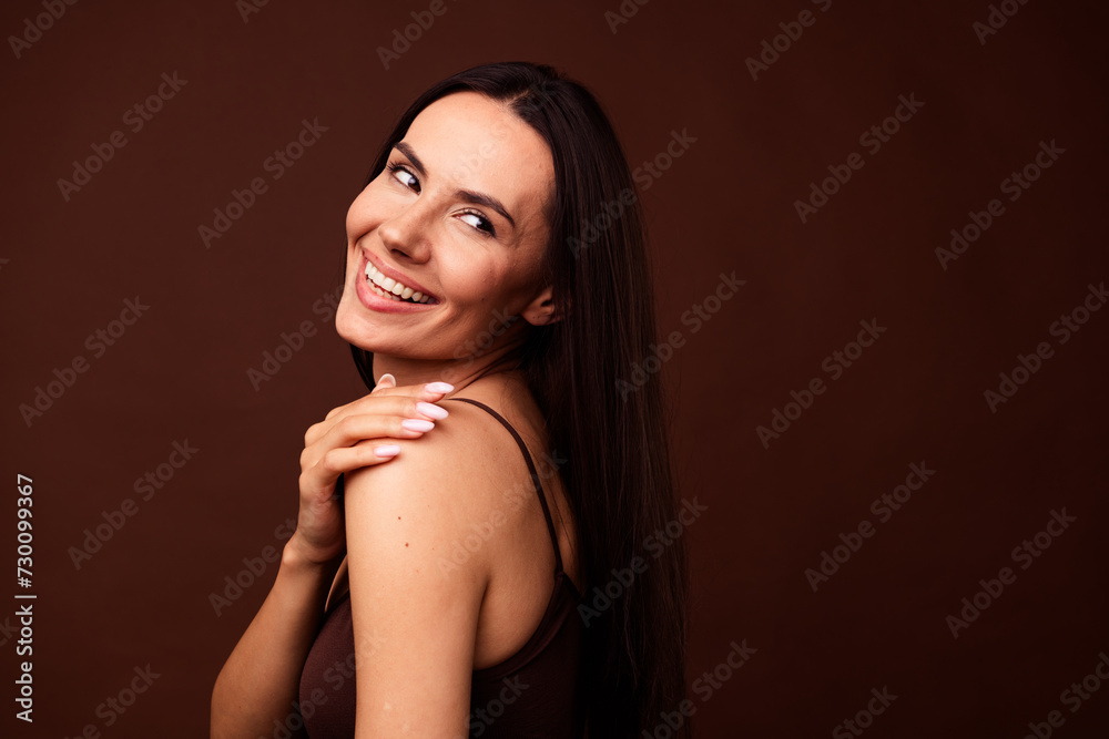 Profile portrait of lovely nice girl arm touch shoulder toothy smile look empty space isolated on brown color background Profile portrait of lovely nice girl arm touch shoulder toothy smile look empty space isolated on brown color background