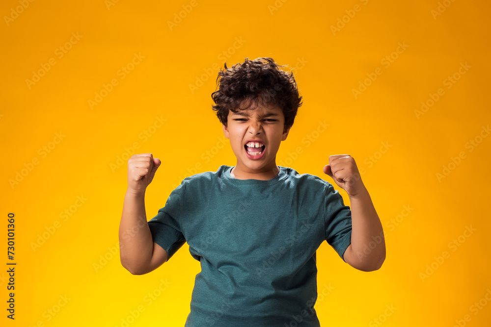 Kid boy showing winner gesture over yellow background. Success and victory concept
