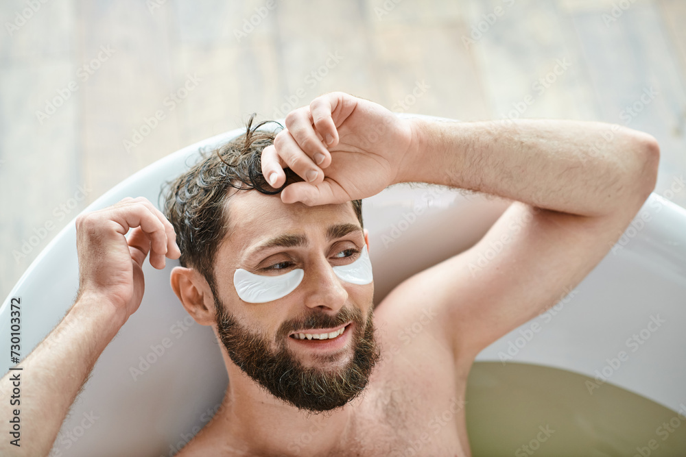 cheerful handsome man with beard relaxing in his bathtub with patches on eyes, mental health cheerful handsome man with beard relaxing in his bathtub with patches on eyes, mental health