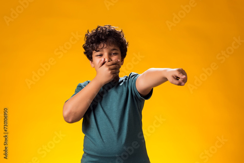 Kid boy laughing at somebody and pointing finger at camera. Bulling concept photo