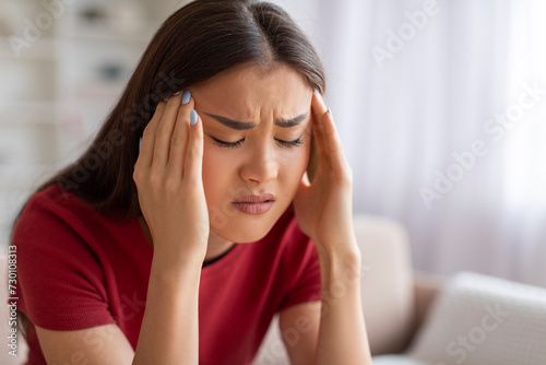 Anxious young asian female touching head with hands and frowning