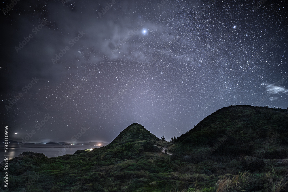 石垣島の平離島展望より眺める雲間の星空と海岸の灯り