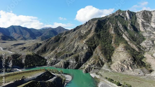 Aerial view of a turquoise river and road snaking through a mountainous terrain. The stunning landscape of the confluence of the Chuya and Katuni rivers in Altai photo