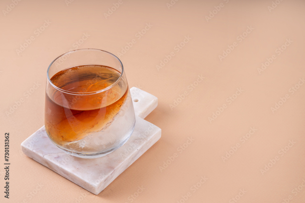 Obraz na plátně Cognac or whiskey with ice, strong alcohol cocktail with frozen glass on light b