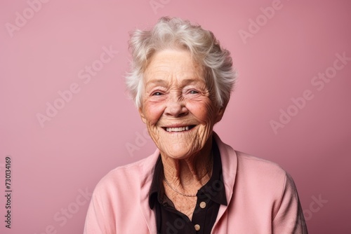 Portrait of smiling senior woman. Isolated on pink background.