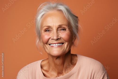 Portrait of smiling senior woman. Isolated on orange background.