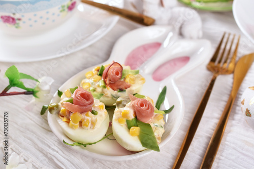 Deviled eggs with ham, peas, corn, chives and mayonnaise on bunny shaped plate for Easter breakfast