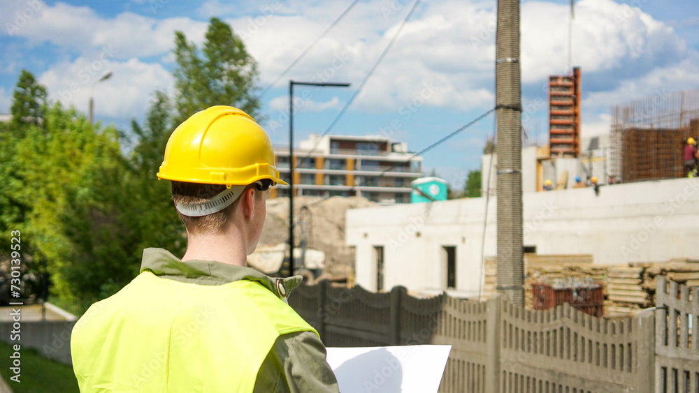 Construction worker looking at construction blueprint at a construction site - Stock photo Construction worker looking at construction blueprint at a construction site - Stock photo