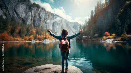 a woman with her arms outstretched standing on a rock overlooking a lake © Alla