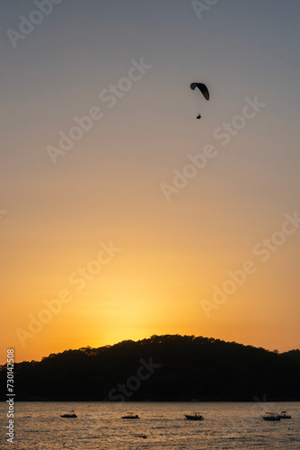 Silhouette of paraglider over the sea during sunset