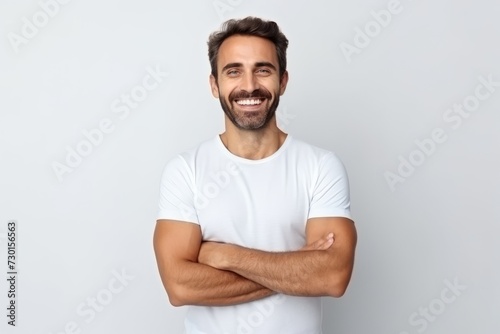 Portrait of a happy young man with arms crossed over grey background © Iigo