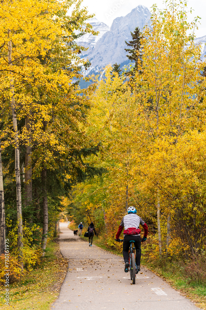 People walking and cycling on the Spur Line Trail in fall season. Canmore, Alberta, Canada.
