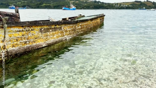 Tilt up of crystalline waters with snail shells on the shore of Dalcahue, calm waters of Chiloé, Chile. photo