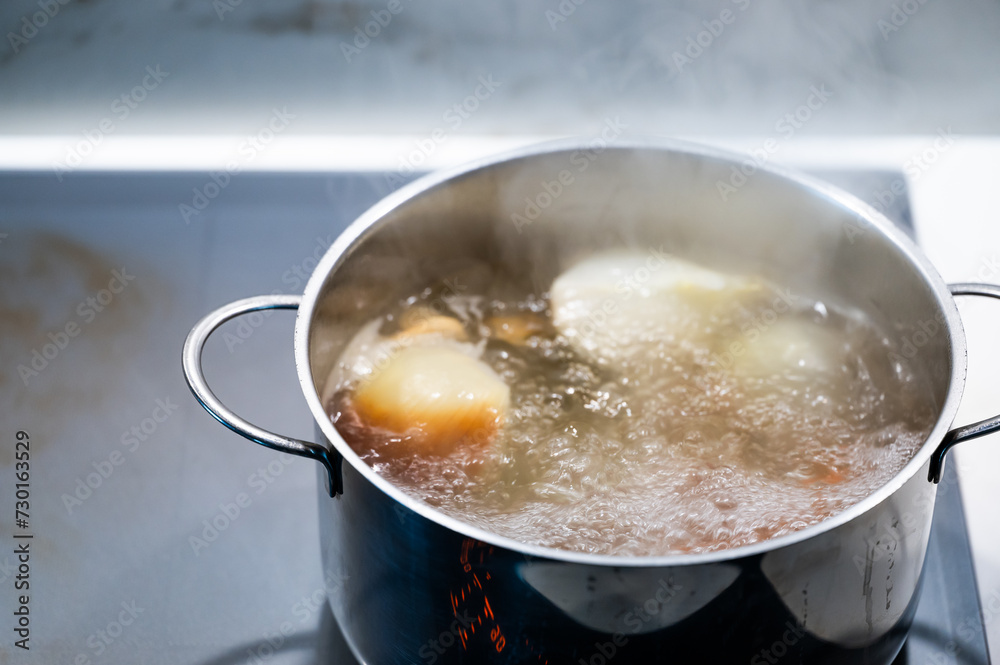 Preparing food with a pot of vegetables on the stove, with steam coming out and the hood on. Preparing food with a pot of vegetables on the stove, with steam coming out and the hood on.
