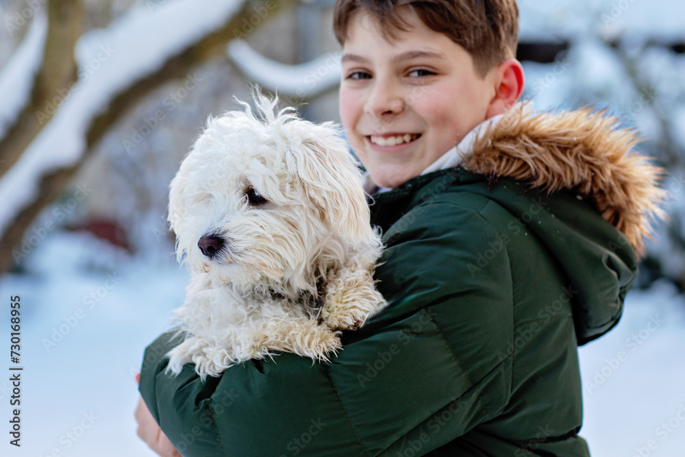 Happy teenager boy and cute maltese puppy together. Handsome child holding his dog, going for a walk. Pet love, family dog. Happy teenager boy and cute maltese puppy together. Handsome child holding his dog, going for a walk. Pet love, family dog.
