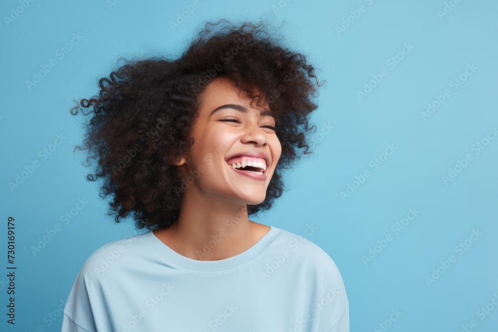 Happy african american woman laughing and looking at camera on blue background Happy african american woman laughing and looking at camera on blue background