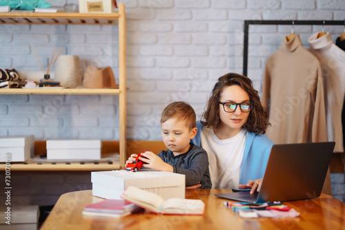 Family Business - telecommuter. mother is working in the internet while her son play.