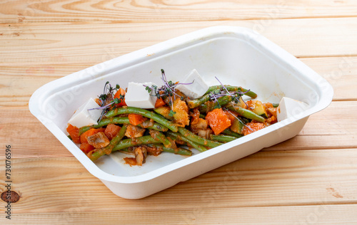 Sautéed vegetables. Healthy diet. Takeaway food. Ecological packaging. On a wooden background.