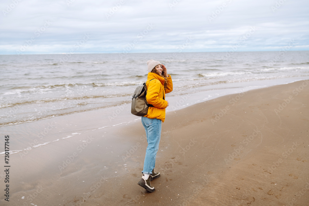 Happy tourist in a yellow jacket and with a backpack posing by the sea. Travelling, lifestyle, adventure. Happy tourist in a yellow jacket and with a backpack posing by the sea. Travelling, lifestyle, adventure.
