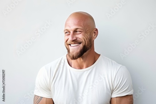 Portrait of a happy bald man smiling against a white background.