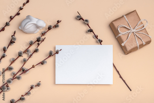 Gift craft box and blank card on a peach background with willow branches and Easter bunny. Easter card.