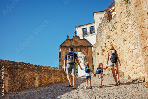Travelers with two kids have a walk in old part of Ronda, Spain
