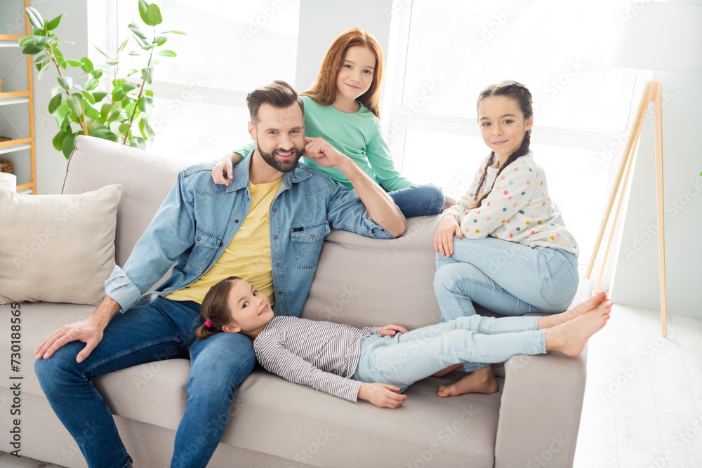 Portrait of four persons cheerful man sit o f sofa with adorable positive girls enjoy free time weekend home indoors