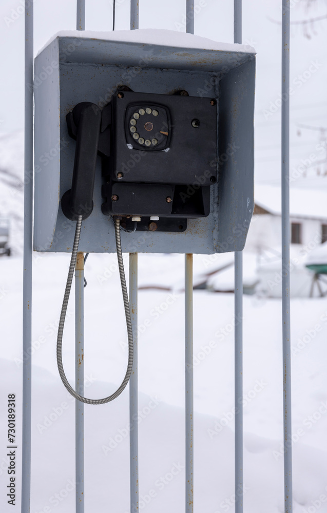 An old black telephone for communication with a checkpoint hangs on a metal fence
An old black telephone for communication with a checkpoint hangs on a metal fence