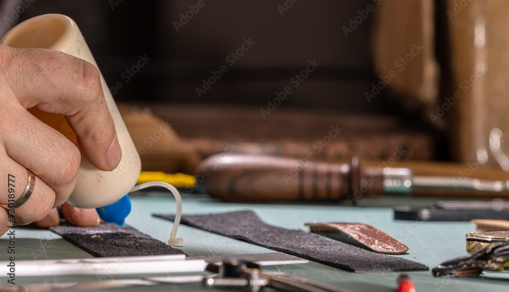 A leather craftsman is making a watch strap.
