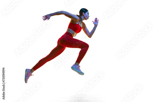 Competitive, concentrated young woman, runner, athlete in motion training, running over white studio background in neon light. Concept of sport, active and healthy lifestyle, sportswear, competition