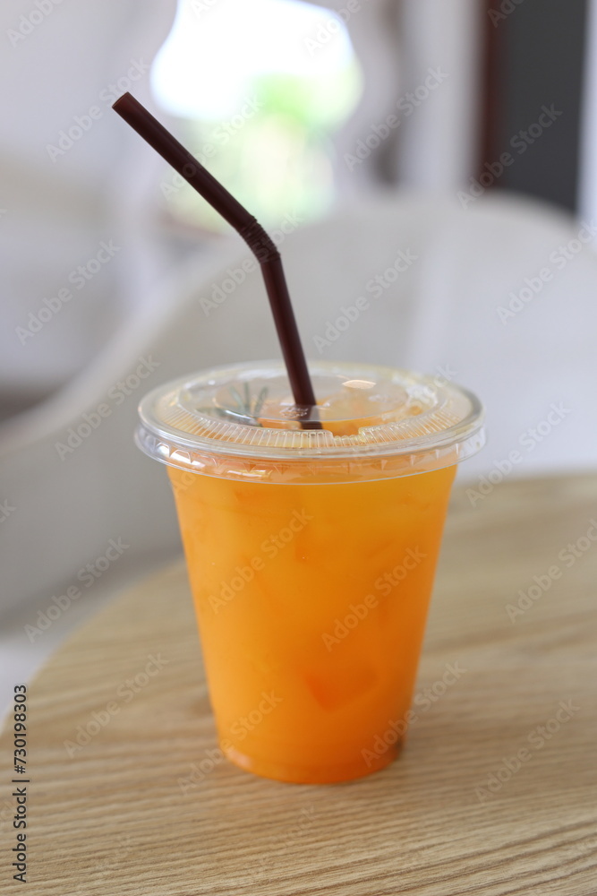 A glass of orange juice is placed on a wooden table in a cafe. Fruit drink concept. food A glass of orange juice is placed on a wooden table in a cafe. Fruit drink concept. food