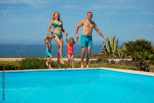 Young parents with two kids have fun on pool resort party