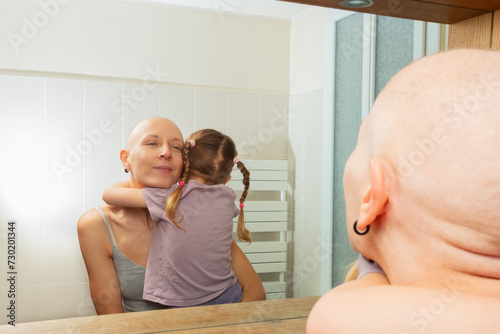 Mother with cancer and child share a tender hug view in mirror