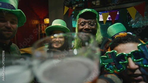 POV UGC footage of clanging glasses of beer with multiracial friends via online video call and celebrating Irish Saint Patricks Day indoors photo