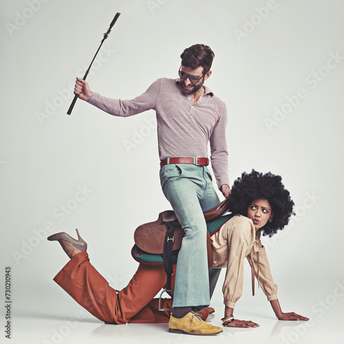 Retro, man and woman or riding crop in studio with piggyback, portrait and funny face for vintage style. Friends, people and 70s outfit with hipster clothes or comic expression with white background