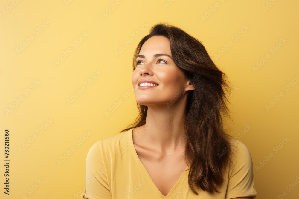 Portrait of happy smiling young woman looking up over yellow background. Portrait of happy smiling young woman looking up over yellow background.