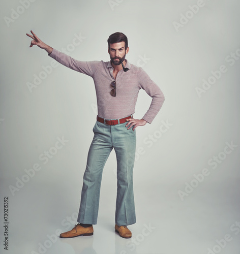 70s, fashion and portrait of man with retro or vintage aesthetic in gray background of studio. Smoking, pipe and person dance with peace and confidence in funky sunglasses and unique style from past