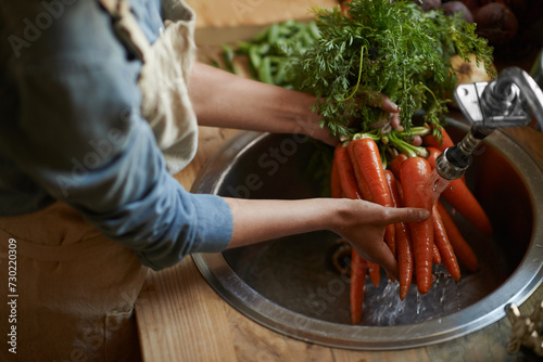 Hands, carrots and washing in sink as vegetable nutrition for wellness ingredient for healthy, salad or organic. Chef, water and clean in kitchen for meal preparation with recipe, vitamins or fibre