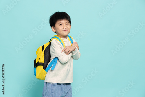 Asian little boy carries a backpack to school in casual clothes isolated on green background, Back to school concept