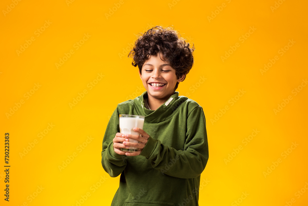 Smiling child boy holding glass of milk over yellow background. Healthy food concept Smiling child boy holding glass of milk over yellow background. Healthy food concept
