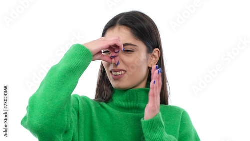 Displeased, annoyed young Caucasian woman covering nose from a stinky, nasty odor over white background. Bad scent, unclean air concept.