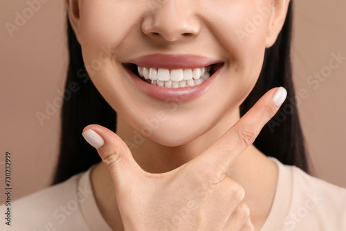 Woman with clean teeth smiling on beige background  closeup