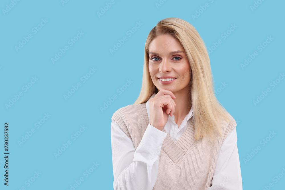Portrait of smiling middle aged woman on light blue background. Space for text Portrait of smiling middle aged woman on light blue background. Space for text