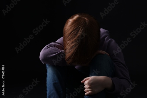 Portrait of sad little boy on black background
